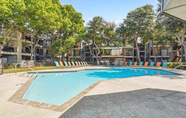 Relaxing pool area with lounge chairs and umbrellas at Laurels of Sendera apartments in Arlington, TX