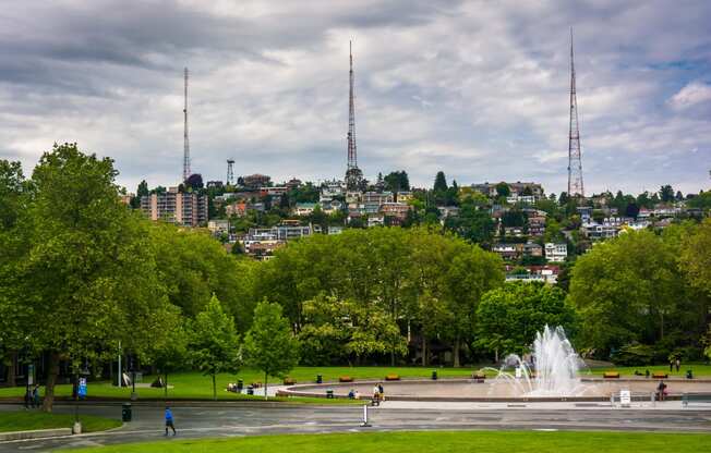 a fountain in the middle of a park with a city in the background at Axis, Seattle, WA, 98109