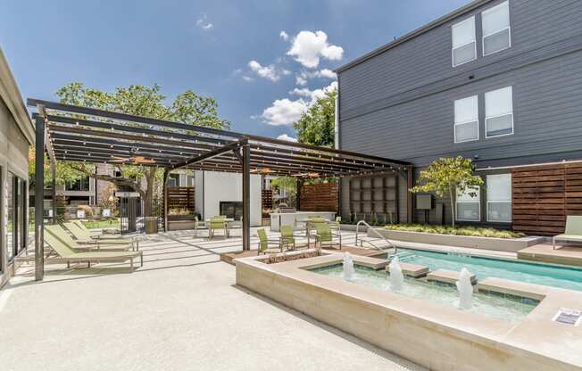 a patio with a hot tub and lounging chairs