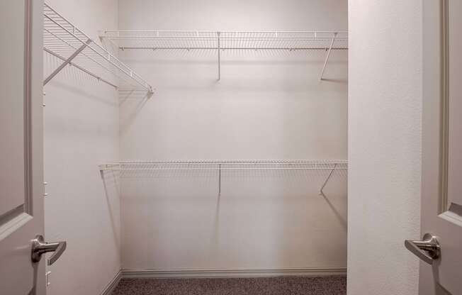 a walk in closet with empty shelves in a white room