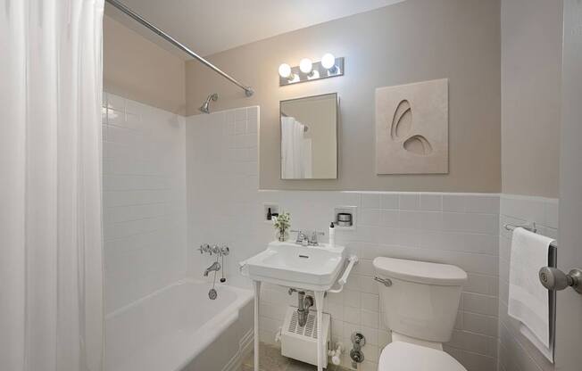 A white bathroom with a toilet, sink, and bathtub.