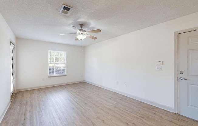 an empty Living room with white walls and a ceiling fan