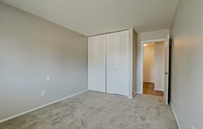 an empty bedroom with white closet doors on the wall