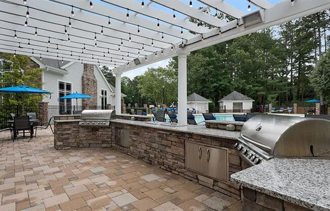 a patio with a grill and a pool in the background at Trails at Short Pump Apartments, Richmond