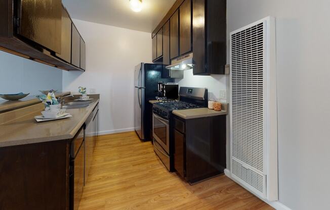 a kitchen with black appliances and wood flooring and a refrigerator