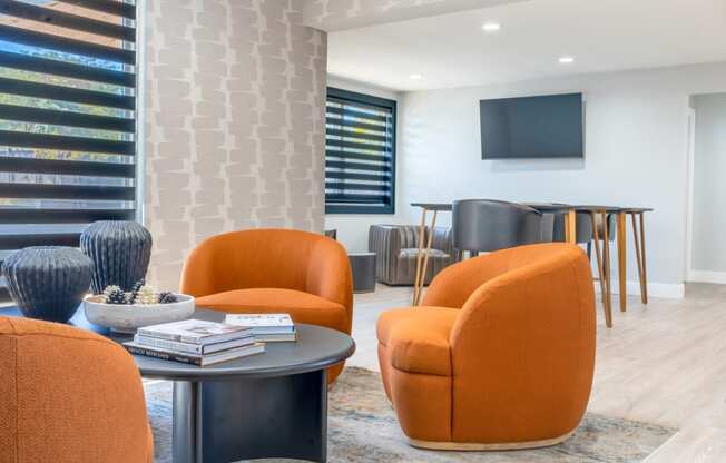 a living room with orange chairs and a table