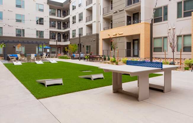 a picnic area with a ping pong table and benches in front of an apartment building