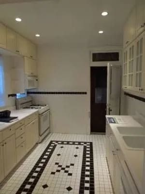 a white kitchen with a black and white tile floor at Bryant II