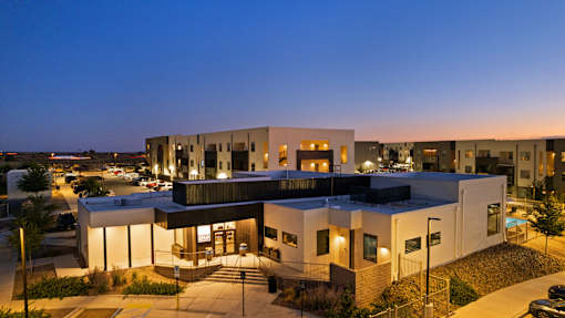 A modern building with a flat roof and a parking lot in front.