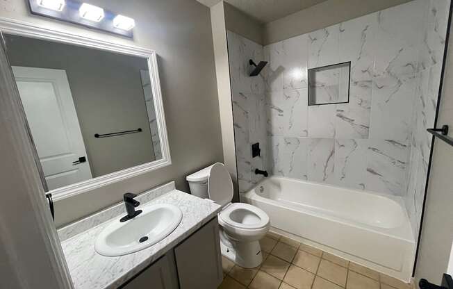 A white bathroom with a sink, toilet, and bathtub.