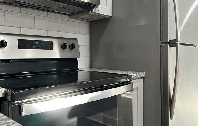 A modern kitchen with a stainless steel refrigerator and oven.
