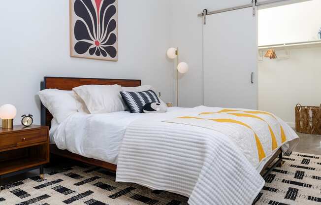 a bedroom with a bed with white sheets and a yellow and black blanket