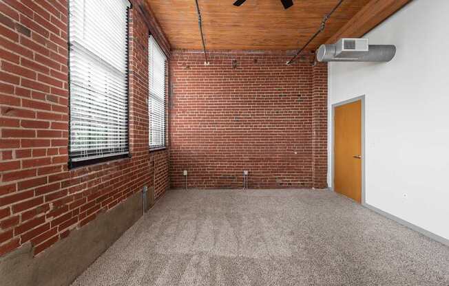 an empty room with a brick wall and a window