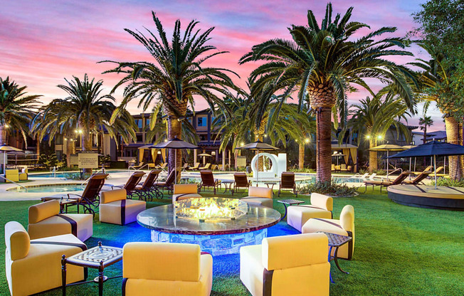 a lounge area with chairs and palm trees at sunset