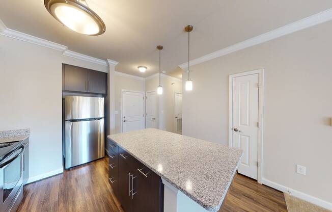 Kitchen with island, dark cabinets, vinyl floors and granite countertops