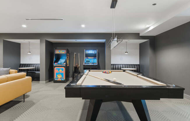 a games room with a pool table and arcade games