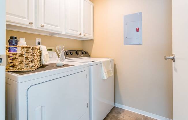 a washer and dryer in a laundry room with white cabinets  at Springfield, Renton, WA