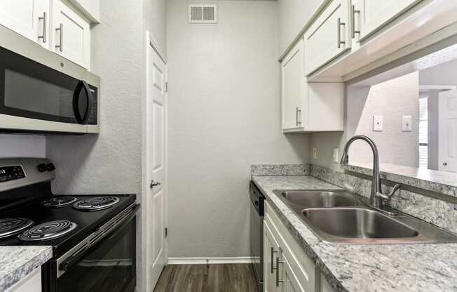 A kitchen with a stove, microwave, and sink.