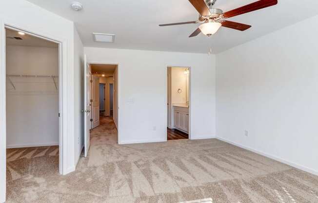 an empty living room with a ceiling fan and a closet