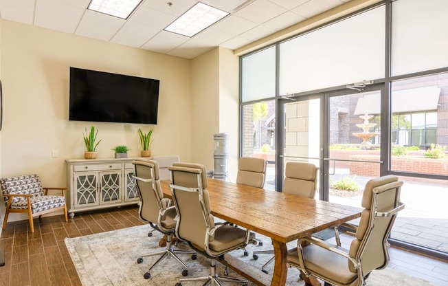 a conference room with a table and chairs and a television