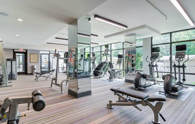 a gym with weights and cardio equipment in a building with large windows