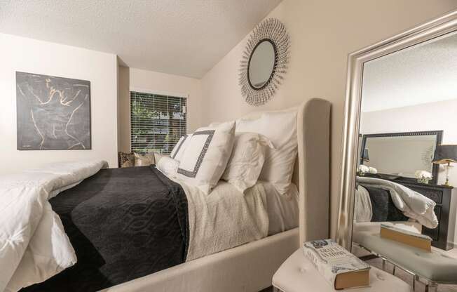 spacious bedroom with a large mirror and a bed with white and black pillows and