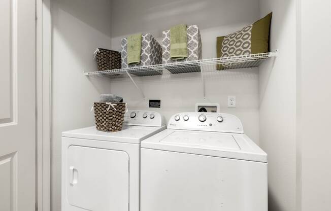 a white washer and dryer in a laundry room with a shelf above it