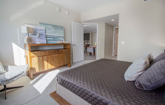 a bedroom with a bed and a dresser and a bathroom