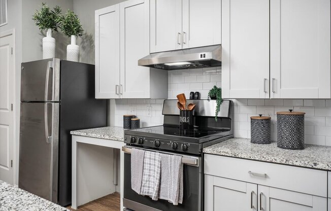a white kitchen with white cabinets and a black stove