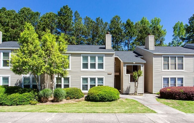 A building with a grey facade and a green tree in front.