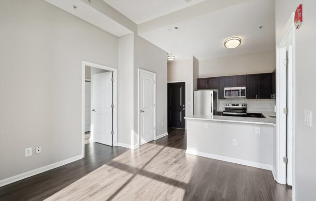 living room and kitchen of a apartment with white walls and wood floors