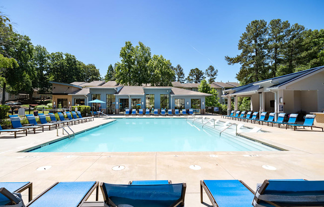 A large swimming pool surrounded by lounge chairs and trees.