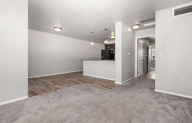 A spacious living room with a grey carpet and white walls.