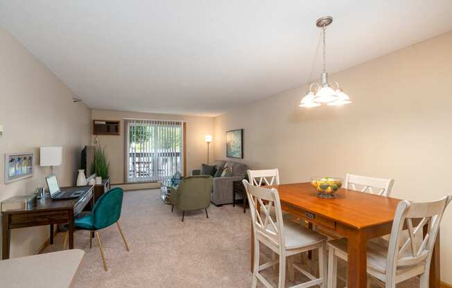 Living room with dining table, couches, and chairs, and a sliding glass door