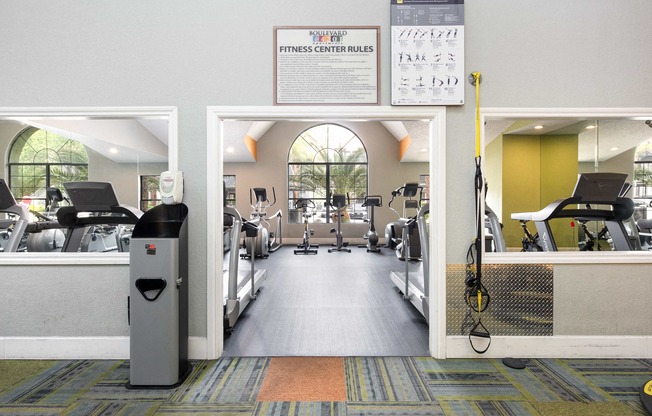 a gym with cardio equipment and a sign on the wall