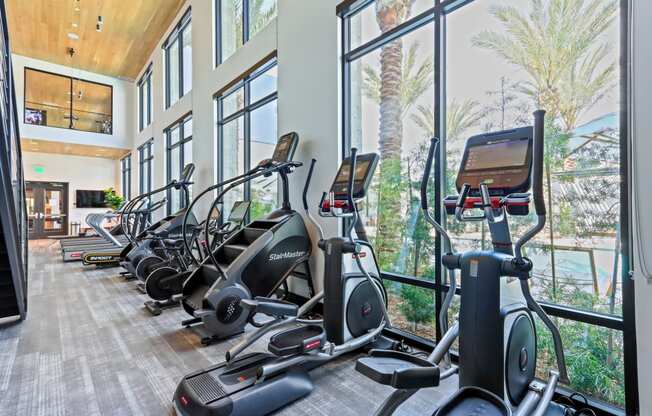 Row of exercise bikes in a fitness room with large windows at Array La Mesa, La Mesa