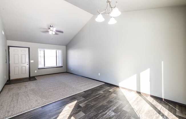 A spacious room with a ceiling fan and a door.