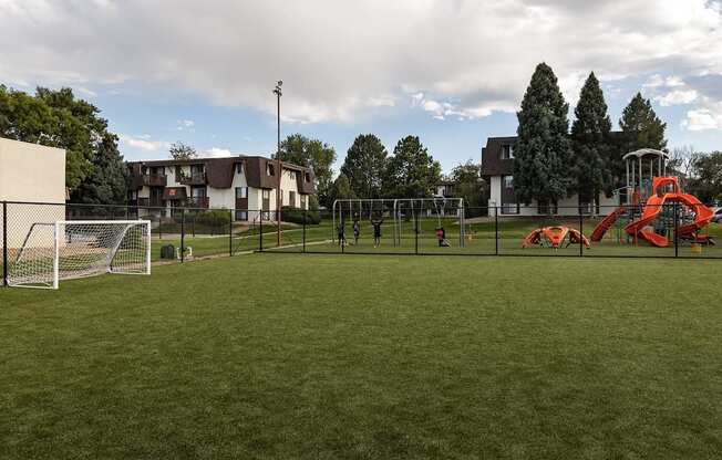 A playground with a red slide and a soccer goal.