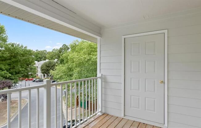 a white door opens to a balcony with a street in the background at Trails at Short Pump Apartments, Richmond