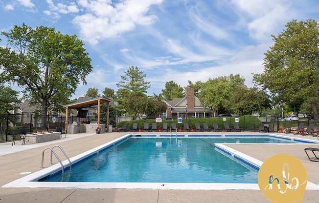 A large outdoor swimming pool surrounded by trees and a covered area.