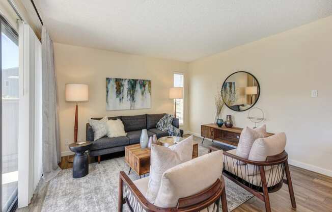 Living room with two tone paint,  Hardwood Inspired Floor, Gray/White Rug, Gray Sofa and Round Mirror  at Silverstone Apartments, Davis, CA