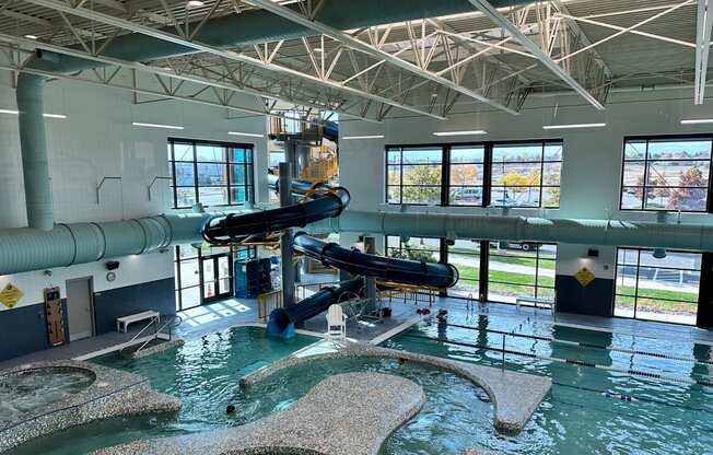 A large indoor water park with a slide and a pool.