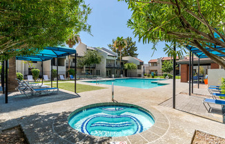 Swimming pool and spa at Sono Tempe Apartments in Tempe, Arizona surrounded by palm trees and community seating.