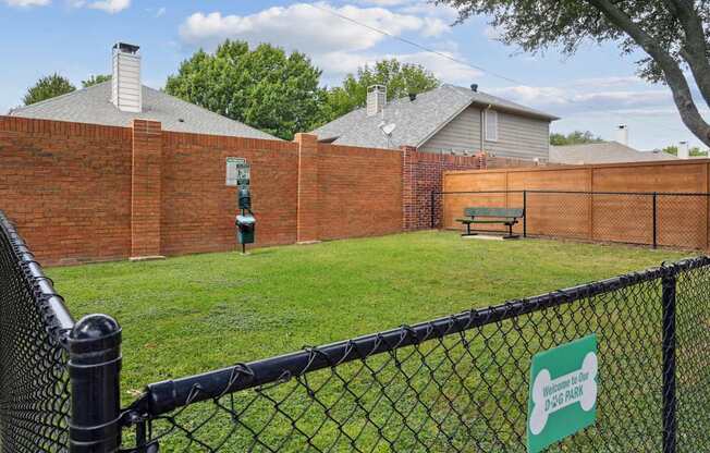 A sign on a fence reads "Welcome to our Dog Park.".