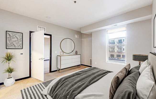 A bedroom with a large bed and a plant on the floor.