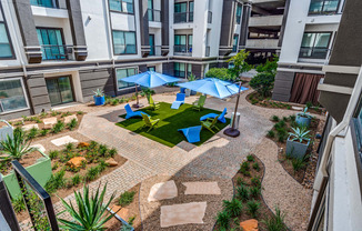 an outdoor area with umbrellas and chairs in an apartment building