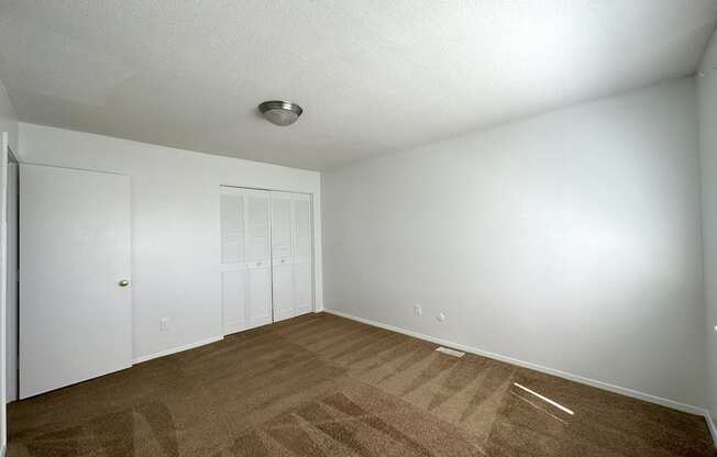 a bedroom with white walls and a brown carpet