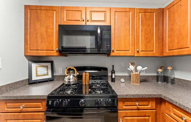 A kitchen with a black stove and wooden cabinets.