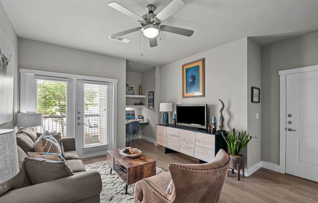a living room with a ceiling fan and a tv