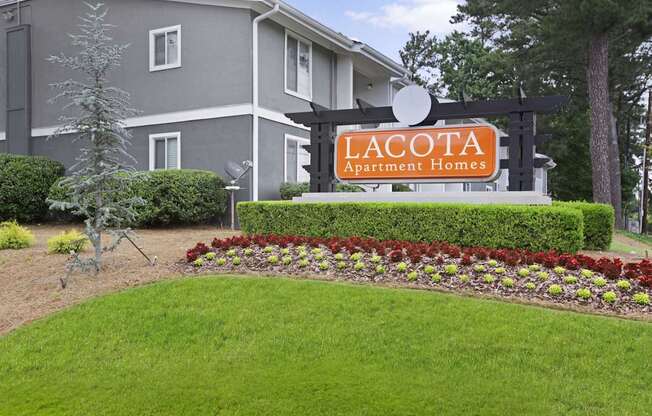A sign for Lacota Apartment Homes stands in front of a building.